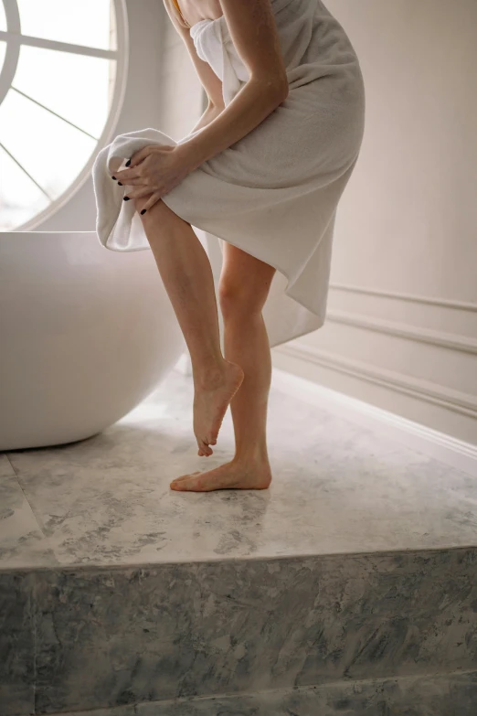 a woman standing in front of a bath tub, by Nicolette Macnamara, trending on pexels, renaissance, looks like varicose veins, wearing white silk, squatting, a woman walking