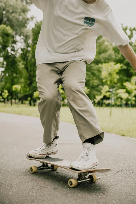 a man riding a skateboard down a street, trending on pexels, realism, brown pants, at a park, plain background, khakis
