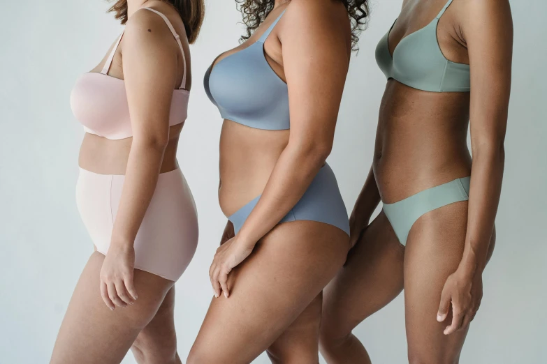 three women in underwear standing next to each other, trending on pexels, muted colours, showing curves, different sizes, colourised