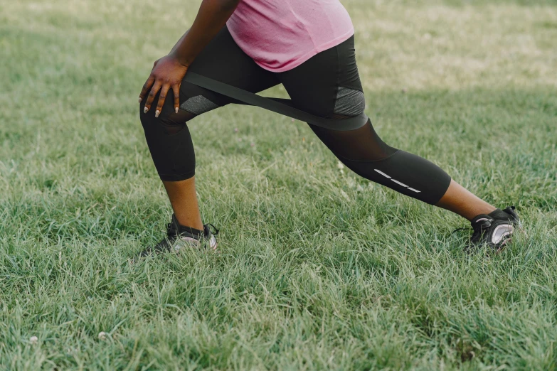 a woman holding a frisbee on top of a lush green field, by Nina Hamnett, pexels contest winner, happening, leggings, black, programming, side view of her taking steps