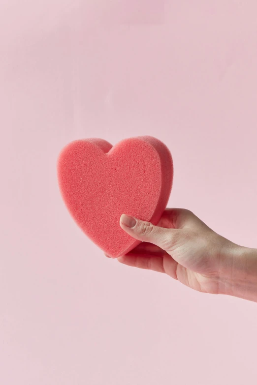 a person holding a heart shaped sponge in their hand, textured base ; product photos, pout, pink power, pixel perfect