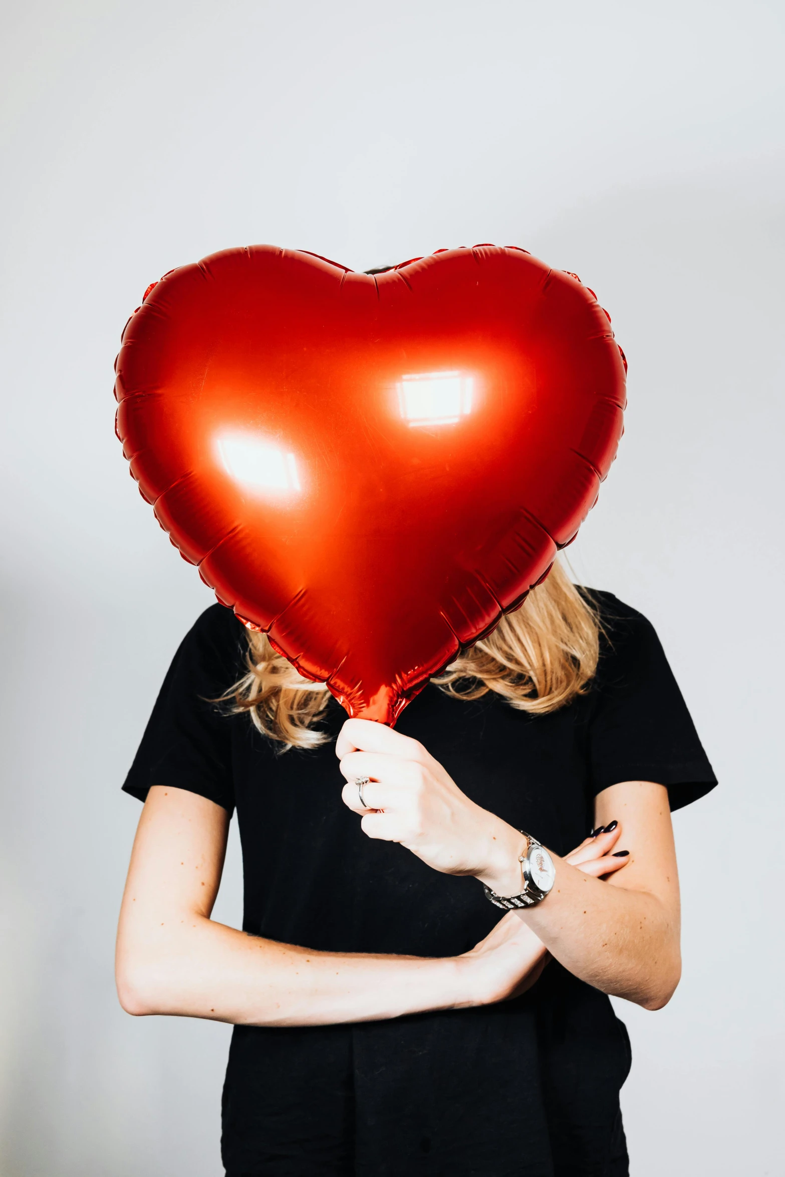 a woman holding a red heart shaped balloon, by Nina Hamnett, trending on pexels, shiny metal, gigantic size, large head, h3h3