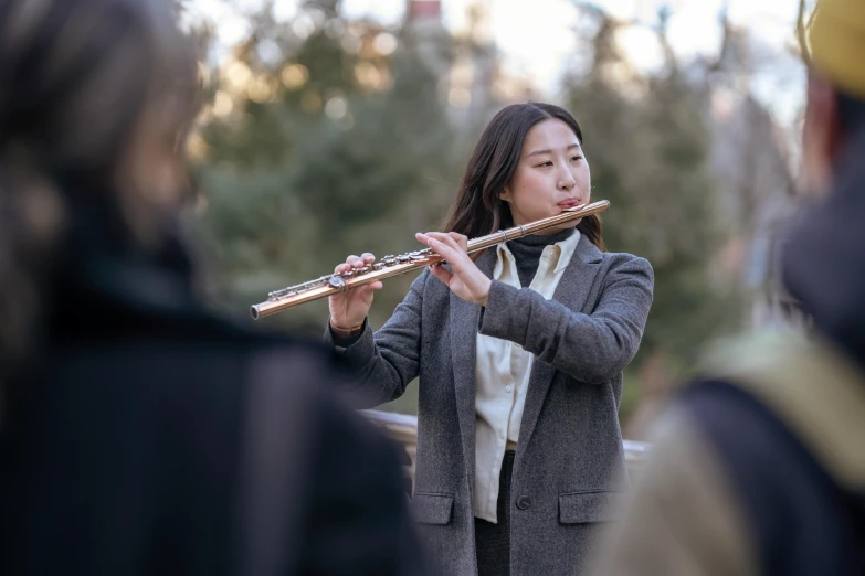 a woman playing a flute in front of a group of people, by Nicolette Macnamara, pexels contest winner, sydney park, calm weather, holding a baguette, peter xiao