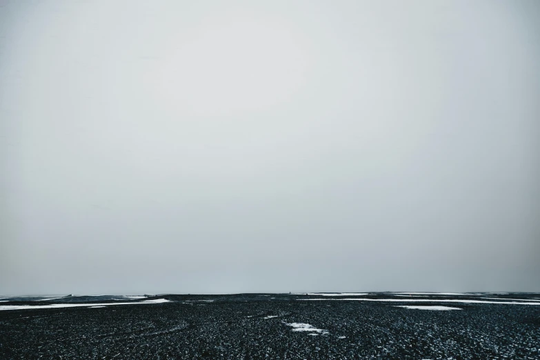 a man flying a kite on top of a snow covered field, inspired by Andreas Gursky, unsplash, postminimalism, iceland landscape, gray fog, landscape of flat wastelands, looking towards the horizon