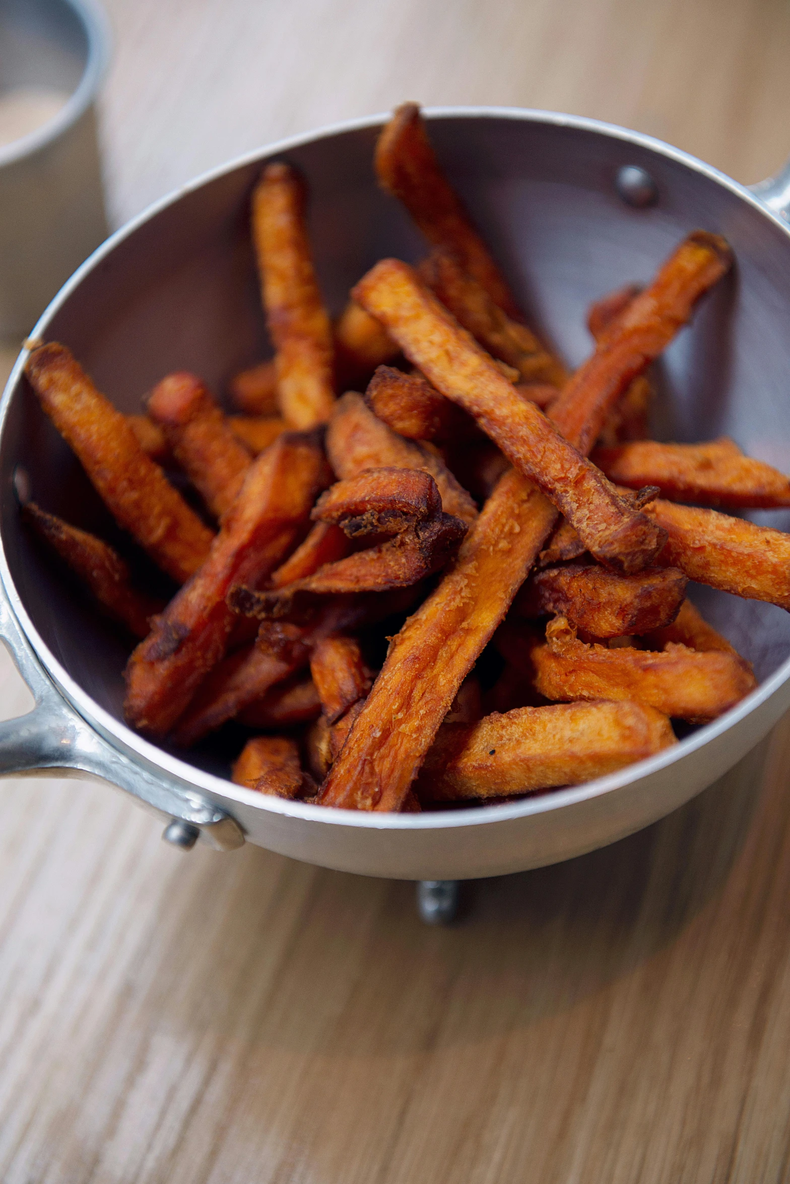 a pan filled with fries sitting on top of a wooden table, carrot, crisps, zoomed in, square