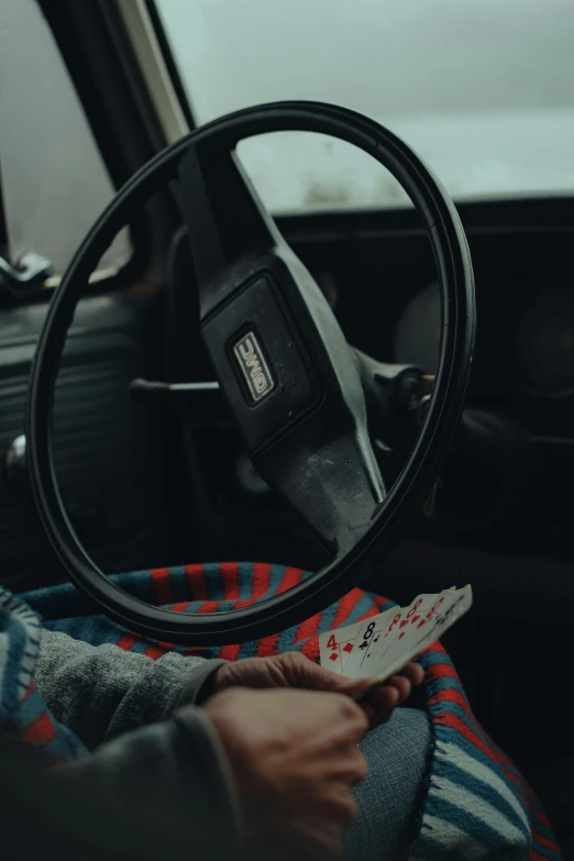 a person sitting in the driver's seat of a car, an album cover, by Elsa Bleda, pexels contest winner, hyperrealism, playing cards, square, cinematic outfit photo