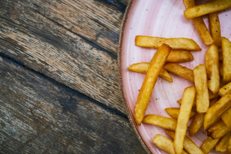 a pink plate topped with french fries on top of a wooden table, unsplash, renaissance, crisps, 🦩🪐🐞👩🏻🦳, woodfired, style of chippy