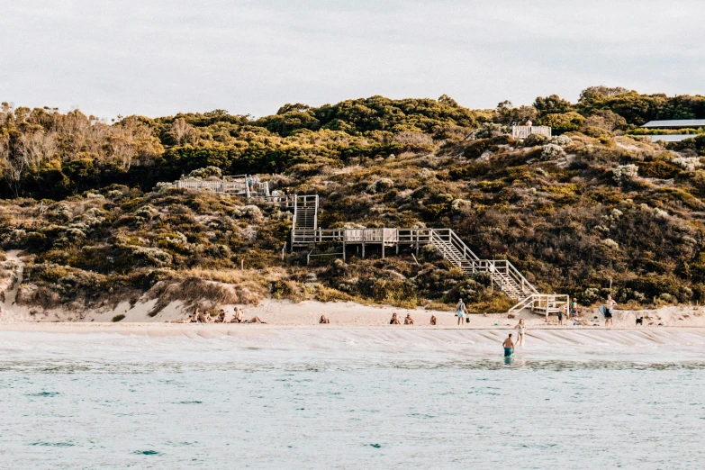 a group of people standing on top of a sandy beach, vibrant foliage, lachlan bailey, white beaches, chairlifts