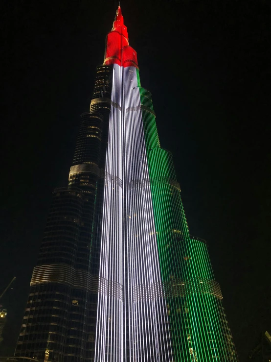 a tall building lit up with green and red lights, hurufiyya, profile image, dubai, fan favorite, stacked image