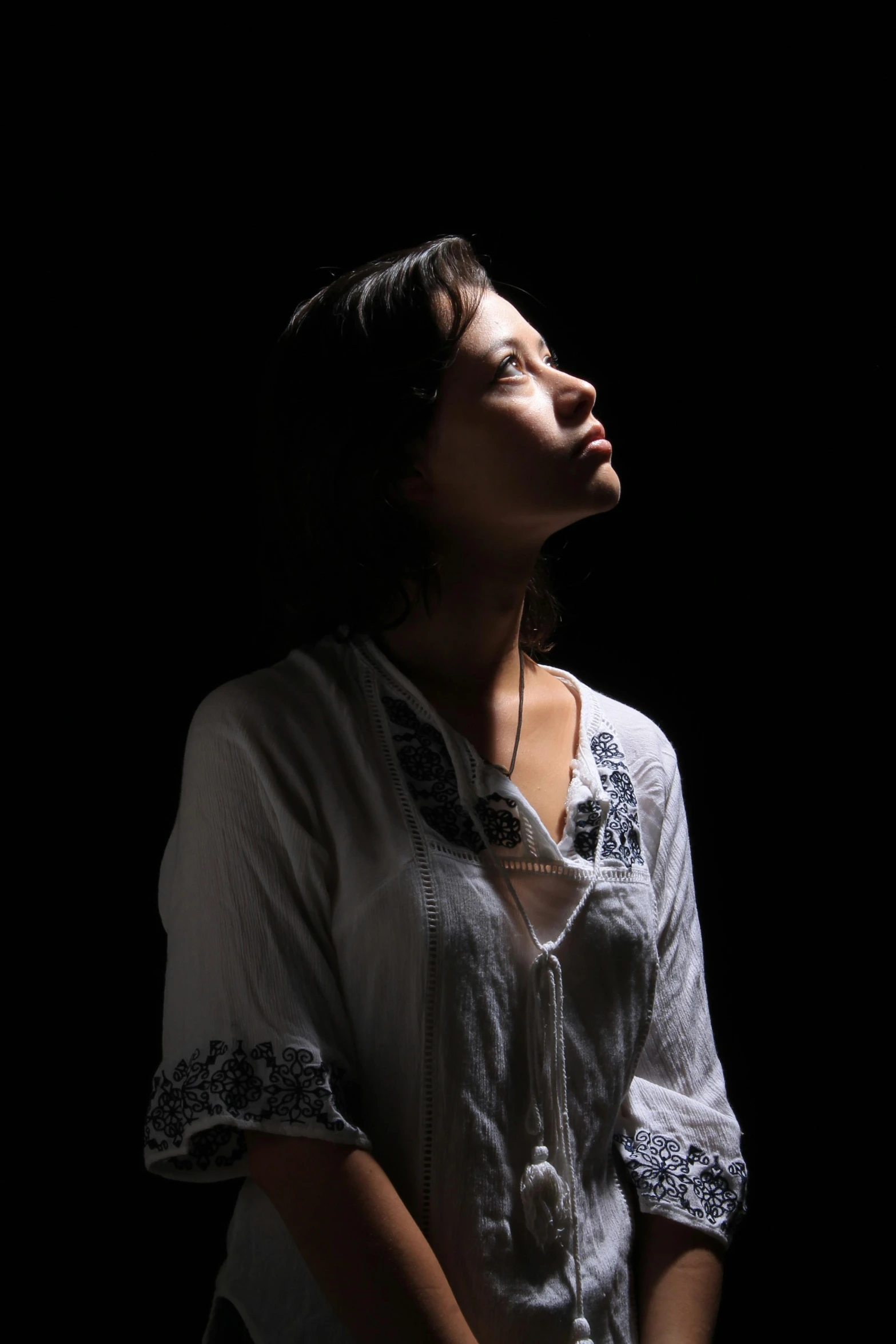 a woman standing in the dark with her eyes closed, inspired by irakli nadar, looking upward, promotional photo, taken in the late 2010s, studio backlight