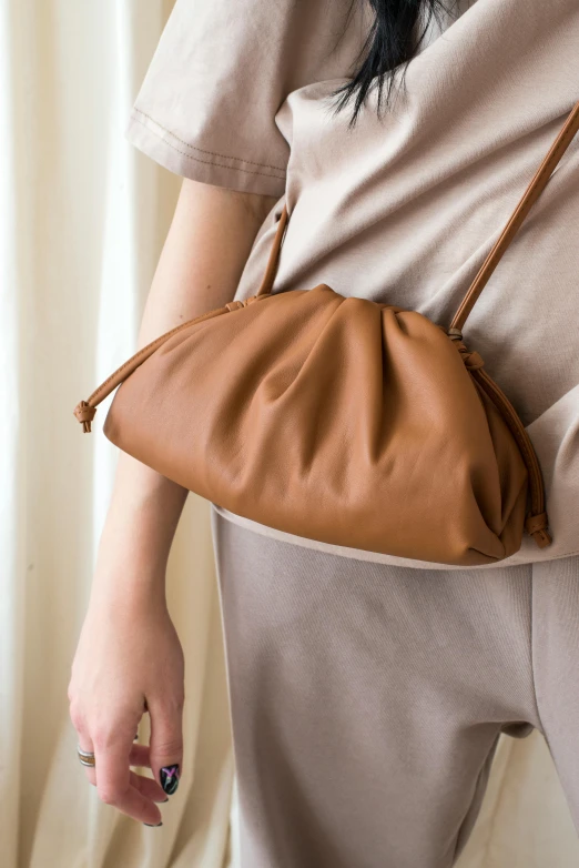 a close up of a person holding a purse, by Simon Gaon, wearing a brown, soft top, けもの, 24mp