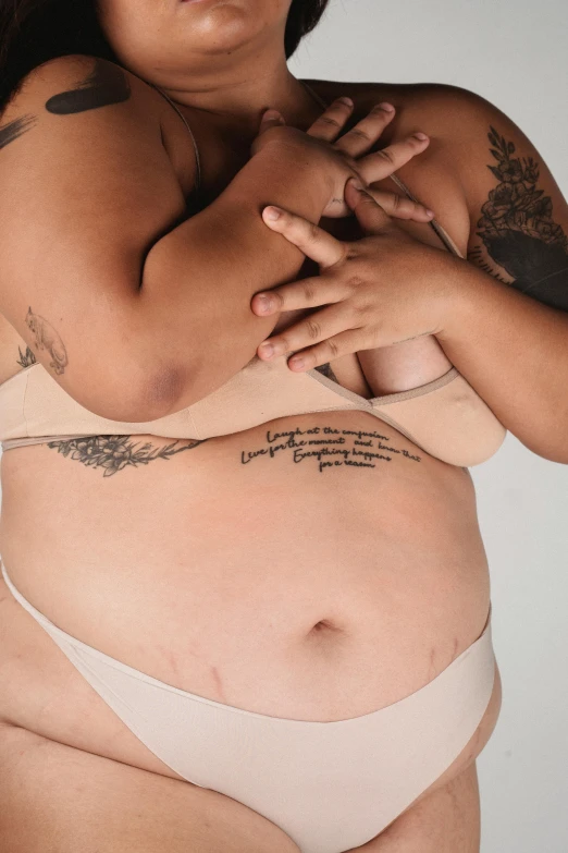 a woman in a bikini posing for a picture, a tattoo, by Jessie Alexandra Dick, trending on pexels, pregnant belly, heavy gesture style closeup, underwear ad, bbwchan