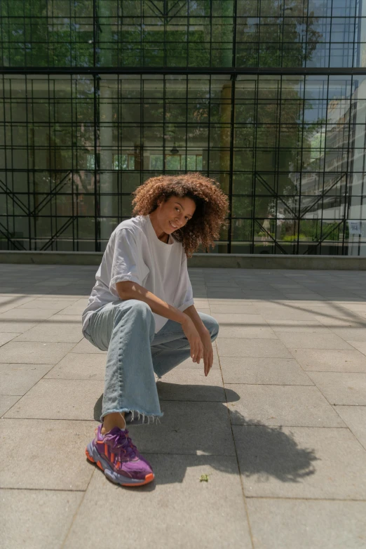 a woman sitting on a skateboard in front of a building, by Nina Hamnett, happening, curly afro, wearing white sneakers, on a marble pedestal, posing for a picture