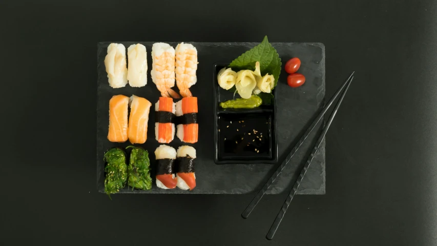 a black plate topped with sushi and chopsticks, inspired by Maki Haku, sōsaku hanga, medium angle, slate, mediterranean, for junior