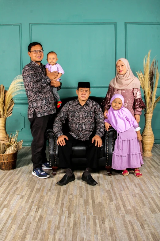 a family posing for a picture in front of a green wall, a picture, by Basuki Abdullah, hurufiyya, high quality image, square, medium poly, islamic