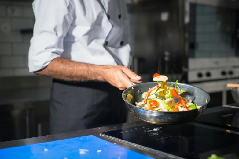 a man cooking vegetables in a frying pan on a stove, by Julia Pishtar, pexels, michelin starred restaurant, avatar image, multiple stories, lachlan bailey