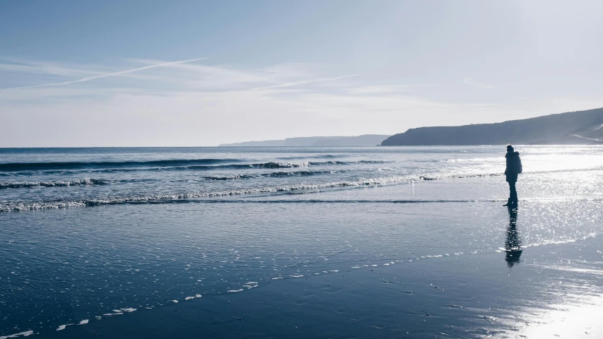 a person standing on a beach next to the ocean, by Andrew Allan, pexels contest winner, minimalism, blue gray, omaha beach, view from the sea, marsden