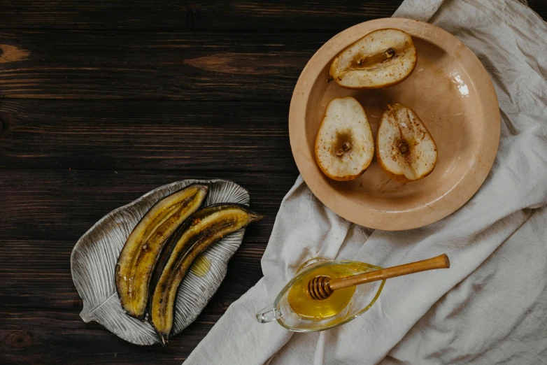 a bowl filled with sliced bananas next to a bowl of honey, a still life, trending on pexels, pear, thumbnail, background image, the plate is on a wooden table