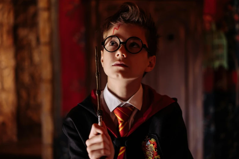 a young boy in a harry potter costume holding a wand, a portrait, trending on pexels, indoor picture, spectacles, 🦩🪐🐞👩🏻🦳, hero