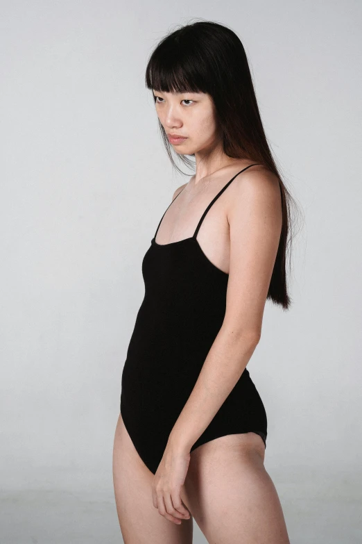 a woman in a black bodysuit posing for a picture, inspired by Ren Hang, unsplash, minimalism, cute girl wearing tank suit, 奈良美智, 🤤 girl portrait, thin aged 2 5