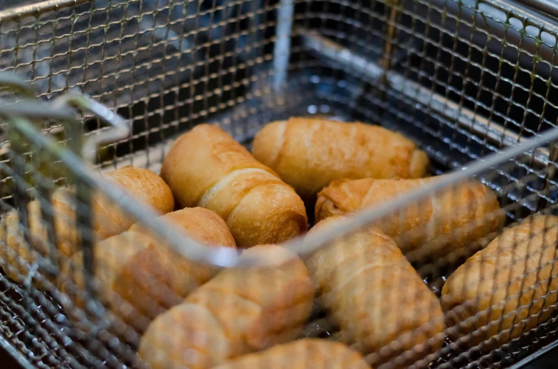 a basket filled with doughnuts sitting on top of a counter, mingei, frying nails, with bread in the slots, deep fried, rectangle