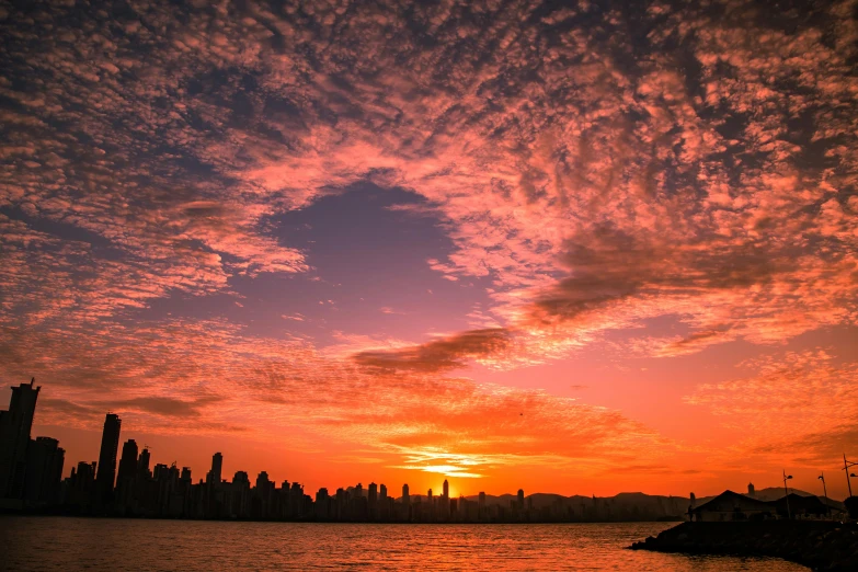 a large body of water with a city in the background, by Matt Stewart, pexels contest winner, romanticism, vibrant sunset dramatic sky, vancouver, orange / pink sky, kowloon