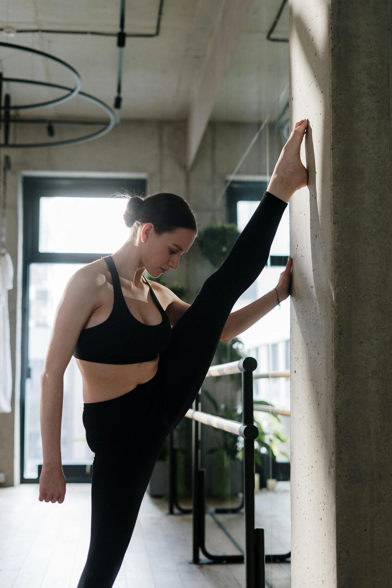 a woman standing on one leg in front of a wall, pexels contest winner, arabesque, working out, sweaty, stretch, low quality photo