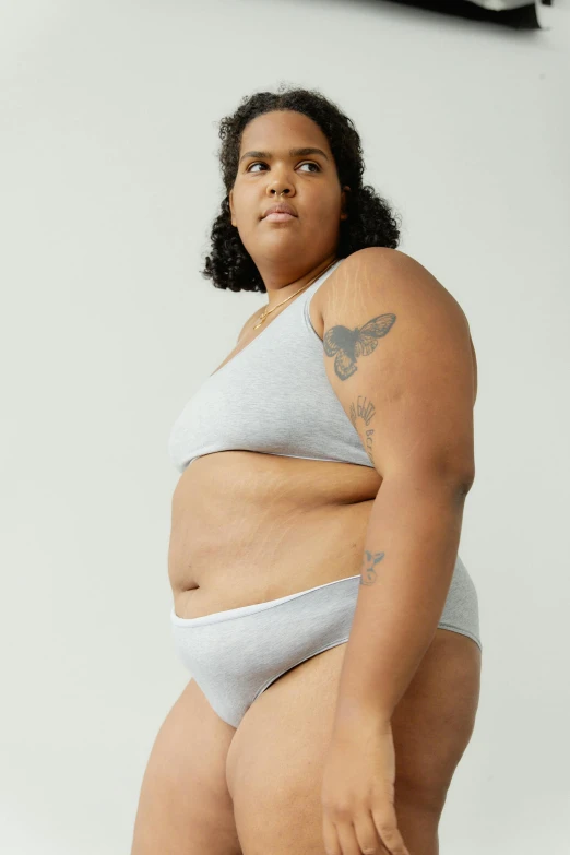 a woman in a bikini posing for a picture, inspired by Louisa Matthíasdóttir, light grey, obese, nonbinary model, catalog photo