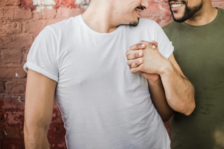 a couple of men standing next to each other, trending on pexels, intimate holding close, background image, playful vibe, gay