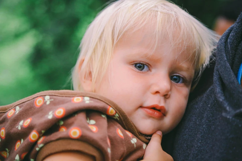 a close up of a person holding a child, by Nina Hamnett, pexels, blonde hair and large eyes, resting on chest, toddler, over his shoulder