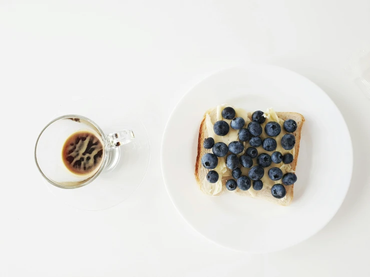 a white plate topped with blueberries next to a cup of coffee, pexels contest winner, minimalism, battle toast, berries inside structure, gif, background image