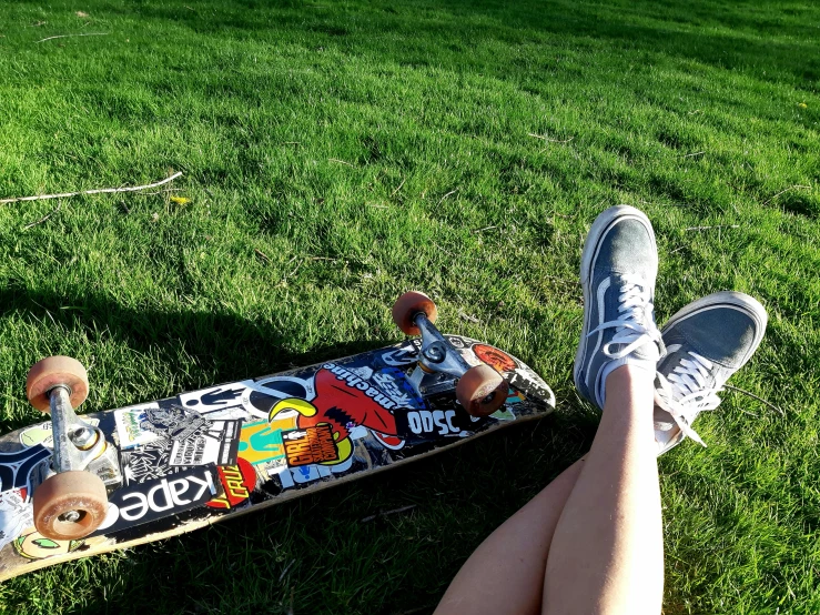 a person sitting in the grass with their feet on a skateboard, a picture, slightly sunny weather, avatar image
