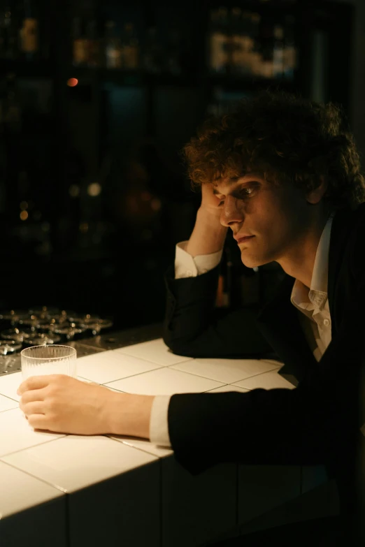 a man sitting at a bar with a glass of wine, an album cover, by Jacob Toorenvliet, unsplash, renaissance, concerned expression, joe keery, ( ( theatrical ) ), studious chiaroscuro
