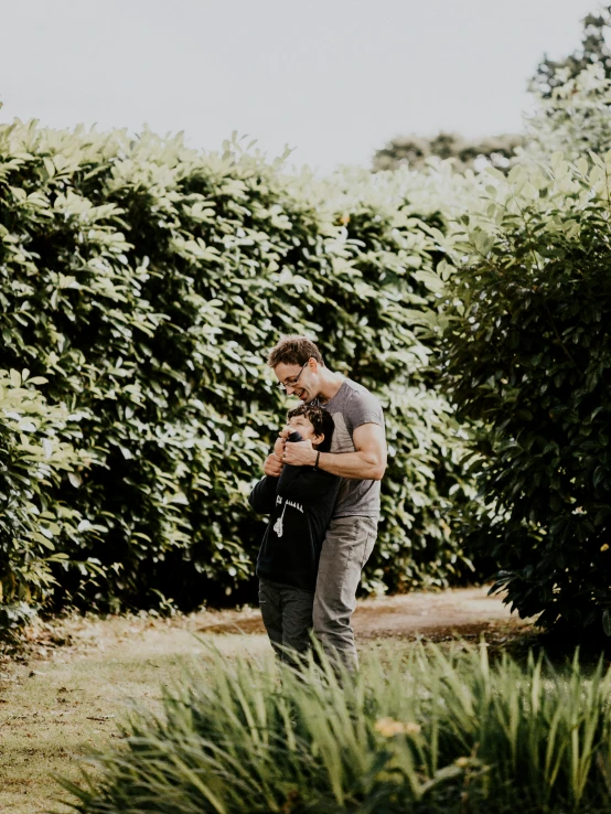 a man standing next to a woman in a field, by Hazel Armour, pexels contest winner, in a verdant garden, two men hugging, beautiful boy, high resolution photo