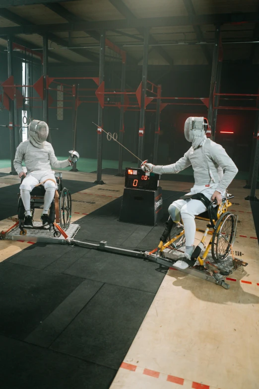 two men in wheelchairs playing a game of fencing, by Adam Marczyński, nasa, 8 k movie still, grey rubber undersuit, female