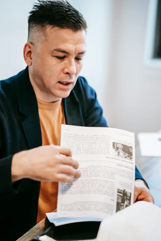 a man sitting at a table reading a book, inspired by Carlos Berlanga, archive material, billy corgan, on white paper, photograph taken in 2 0 2 0