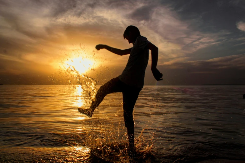 a person kicking a soccer ball in the water, by Sebastian Spreng, pexels contest winner, sun down, teen boy, thumbnail, islamic