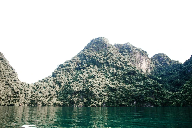 a body of water with a mountain in the background, inspired by Ren Hang, sumatraism, view from the lake, limestone, low quality photo, fan favorite