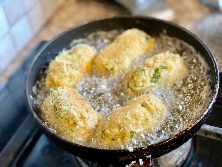 a frying pan filled with fried food on top of a stove, 9 peacock tails, thumbnail, italian, butter