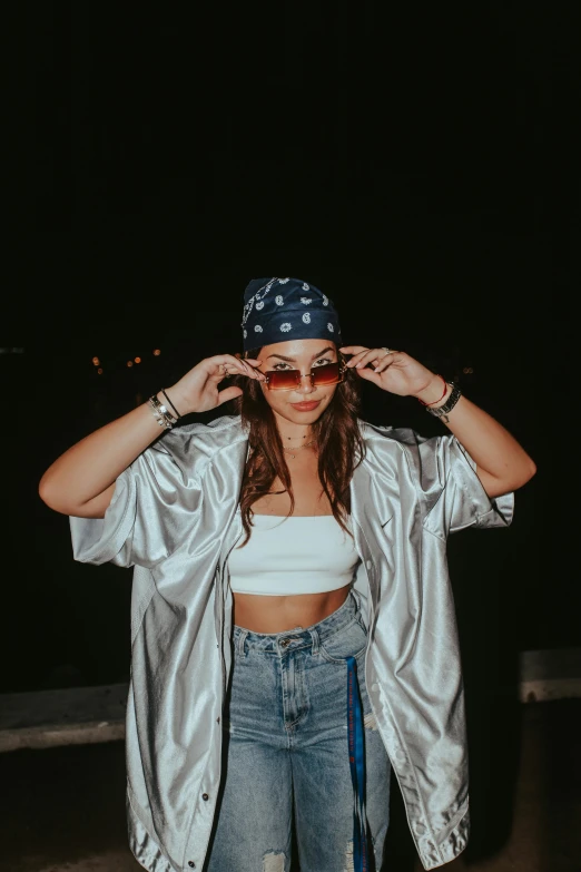 a woman standing in a parking lot at night, an album cover, inspired by Ion Andreescu, trending on pexels, graffiti, bandanas, silver garment, croptop, aviators