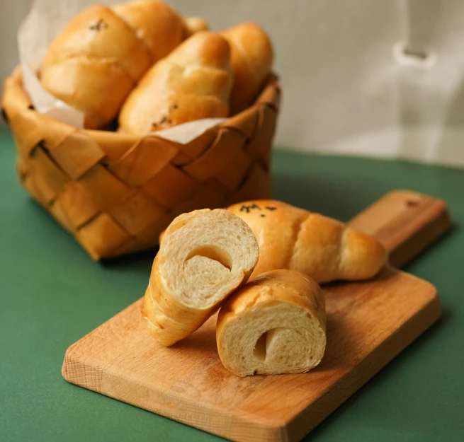 a basket of bread sitting on top of a wooden cutting board