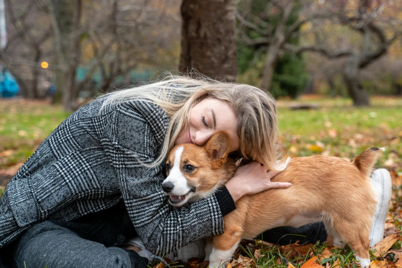a woman hugging a small brown and white dog, by Julia Pishtar, pexels contest winner, cute corgi, autumn season, in australia, teenager girl