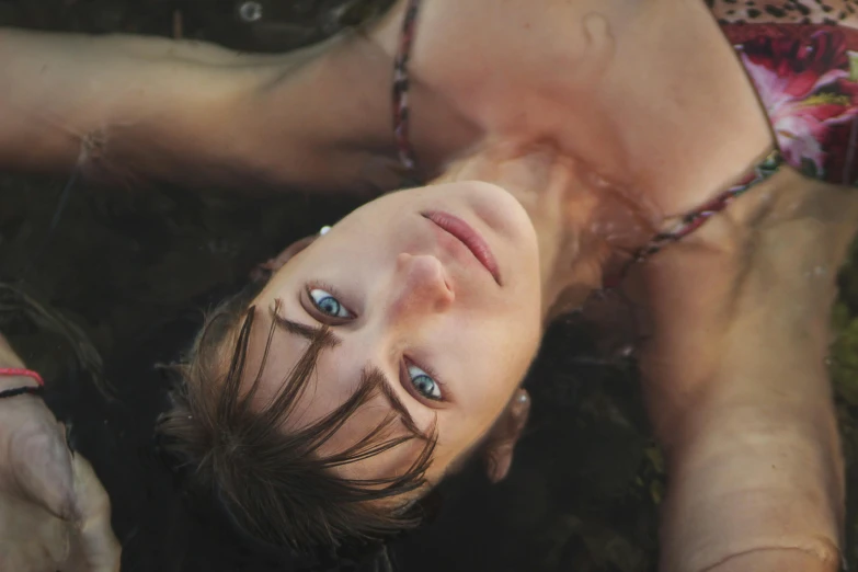 a woman laying on top of a lush green field, inspired by Elsa Bleda, pexels contest winner, renaissance, half face in the water, upside down stranger things, with anxious piercing eyes, portrait of max caulfield