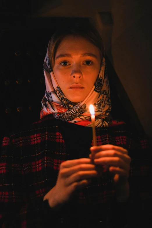 a woman holding a lit candle in her hands, hurufiyya, movie still 8 k, wearing a head scarf, greta thunberg, promo image