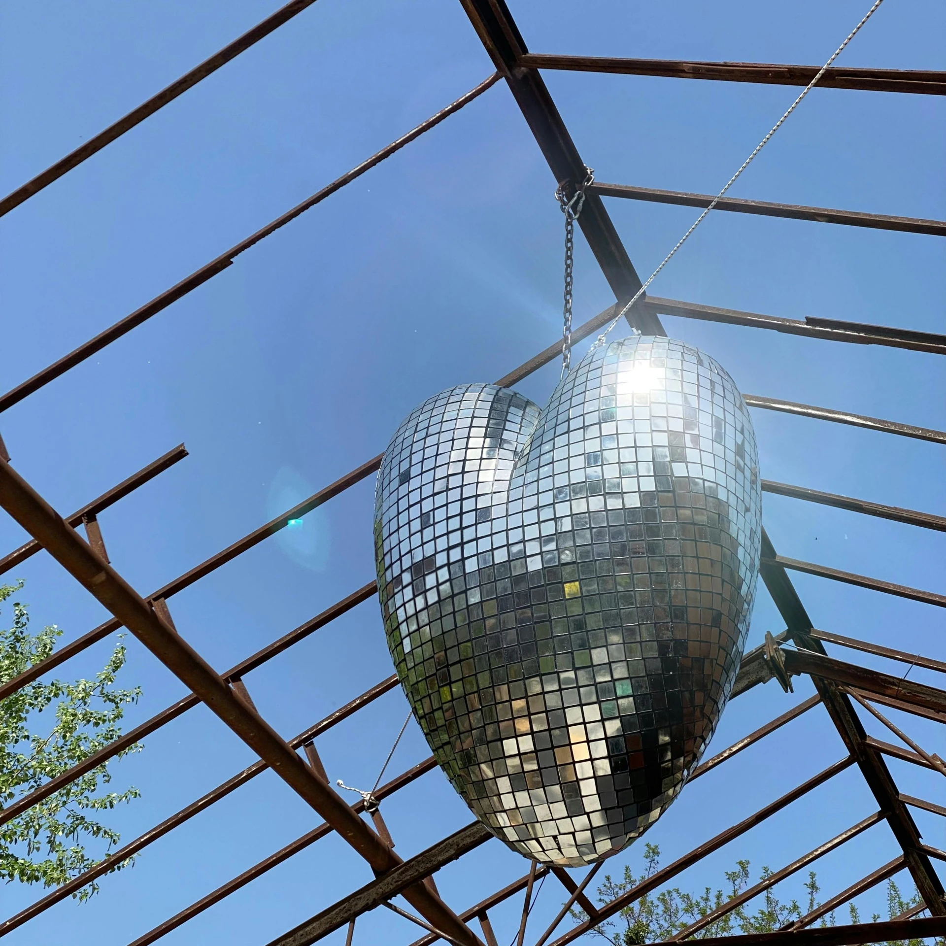 a disco ball hanging from the ceiling of a building, an album cover, unsplash, temporary art, glass-cast heart, outdoor rave, 👰 🏇 ❌ 🍃, metal sculpture