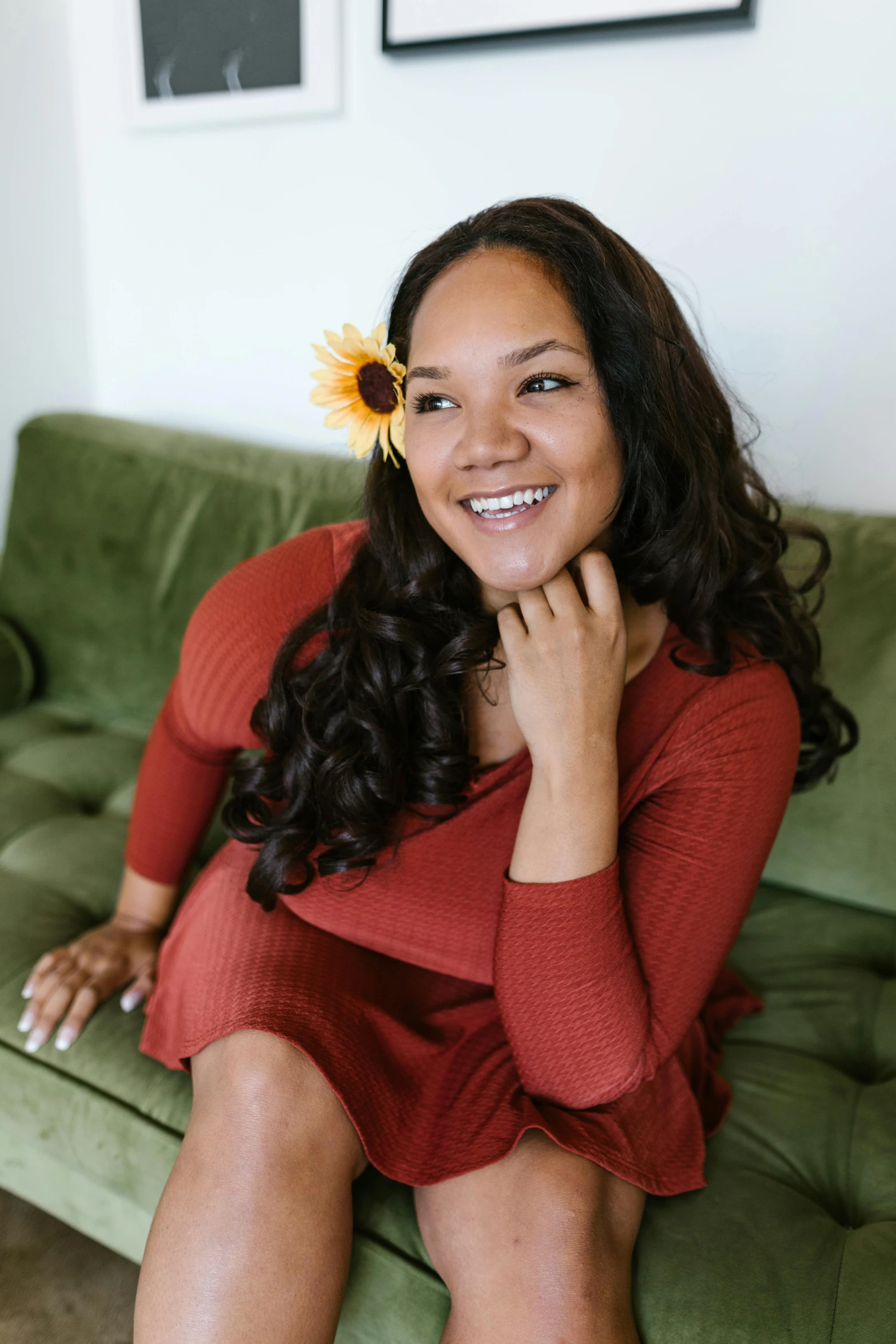 a woman sitting on a green couch with a flower in her hair, mixed-race woman, joy ang, fall season, plus-sized