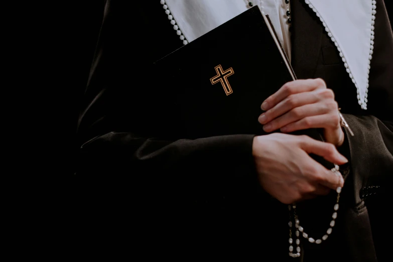 a nun holding a rosary and a bible, an album cover, unsplash, background image, lgbtq, exorcist, exquisite black accessories