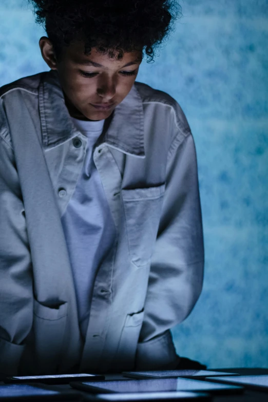 a man sitting in front of a laptop computer, an album cover, inspired by Hiromitsu Takahashi, unsplash, hyperrealism, jean jacket, blue and grey, labcoat, portrait of a japanese teen