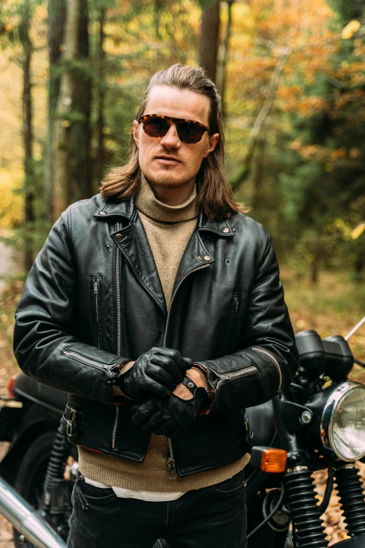 a man standing next to a motorcycle in the woods, with dark brown sunglasses, felix englund style, profile image, leather gloves