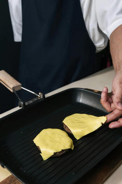 a close up of a person cooking food on a grill, inspired by Gillis Rombouts, melted cheese, koji morimoto shinjuku, yellow, square